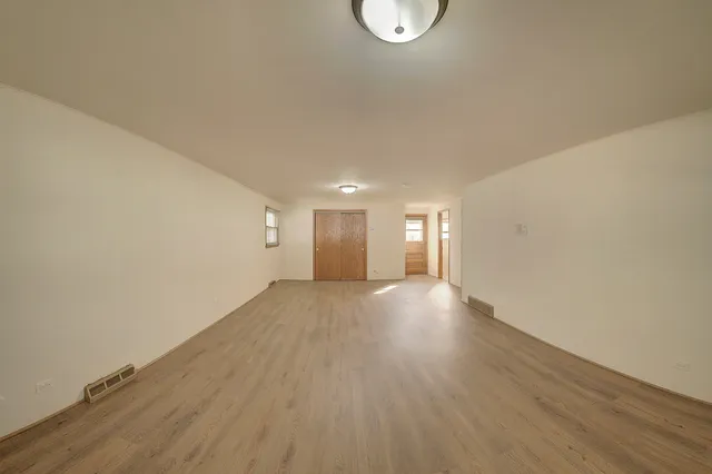 a view of an empty room with wooden floor and window