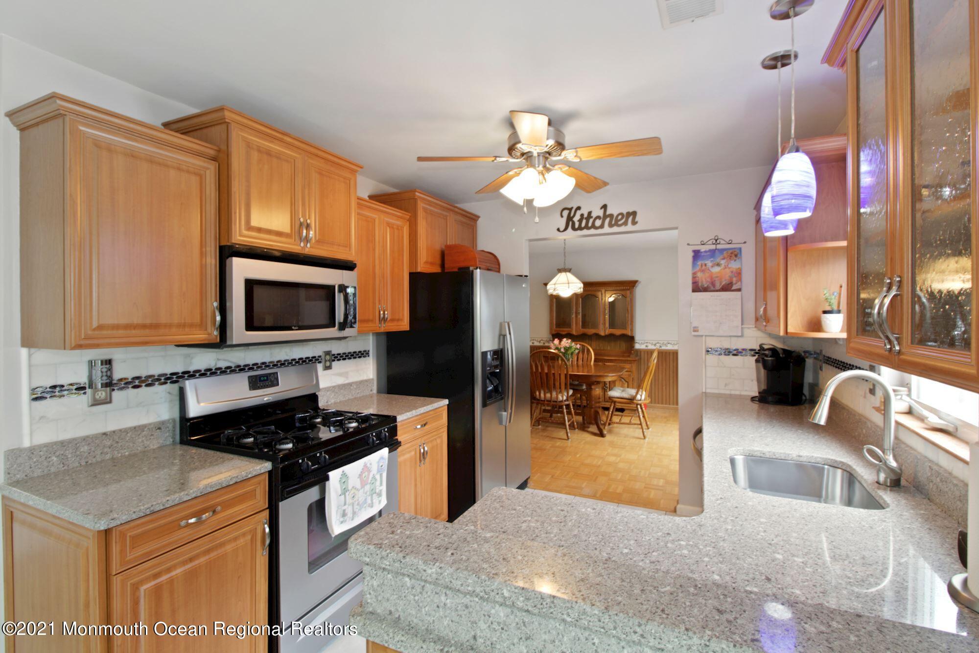 8 Derringer Drive Howell, NJ 07731 - Photo 17 of 33 a kitchen with stainless steel appliances granite countertop a stove top oven a sink a dining table and chairs with wooden floor