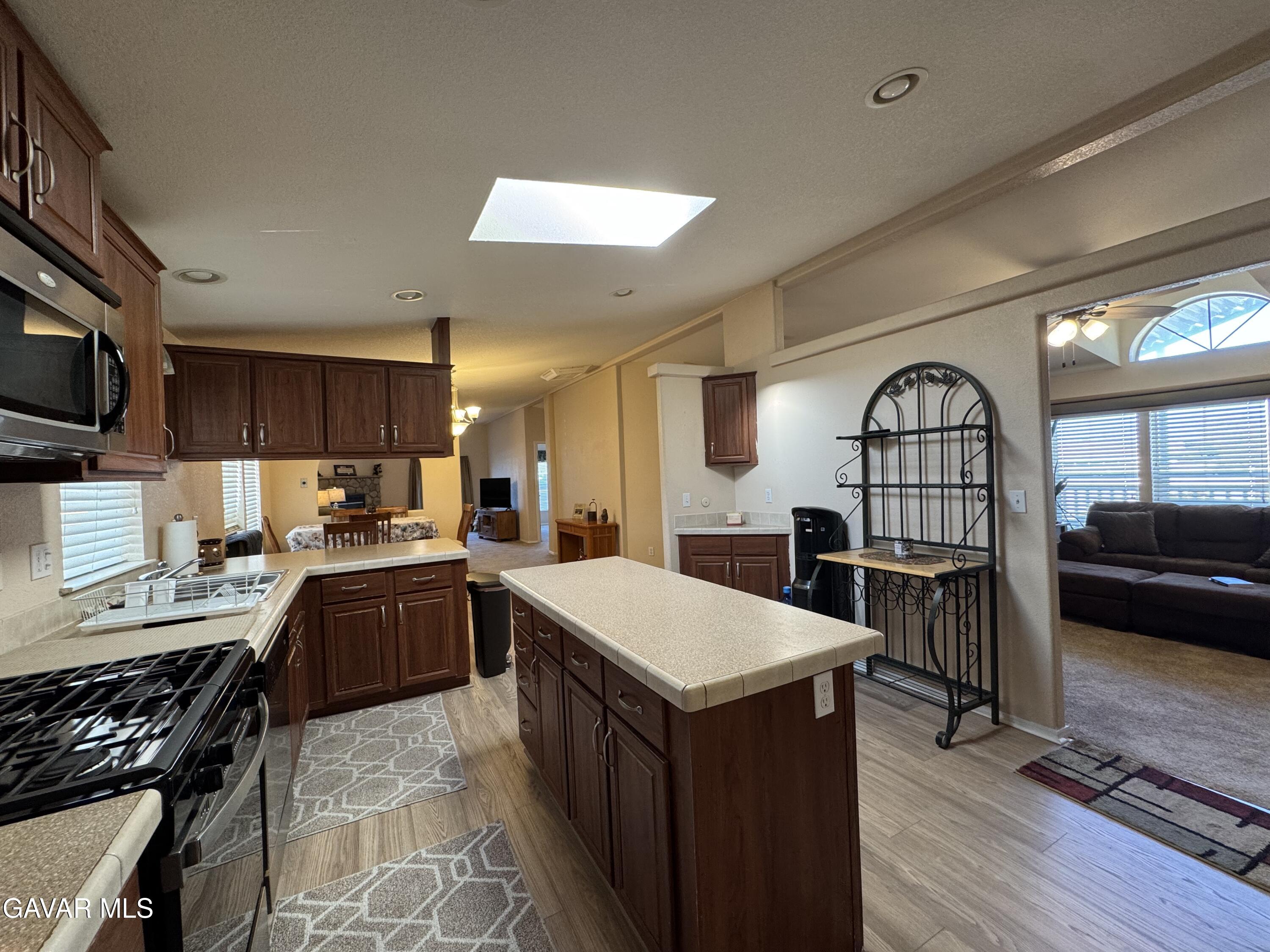 2000 Windflow Drive Rosamond, CA 93560 - Photo 15 of 48 a large kitchen with stainless steel appliances granite countertop a stove top oven a sink a dining table and chairs with wooden floor