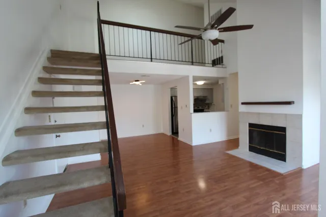 a view of an empty room with wooden floor fireplace and a window