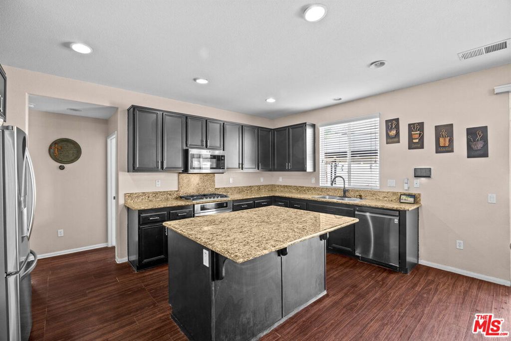 26692 Rim Creek Path, Unit PATHWAY Menifee, CA 92584 - Photo 9 of 41 a kitchen with stainless steel appliances granite countertop a stove a sink dishwasher and a refrigerator