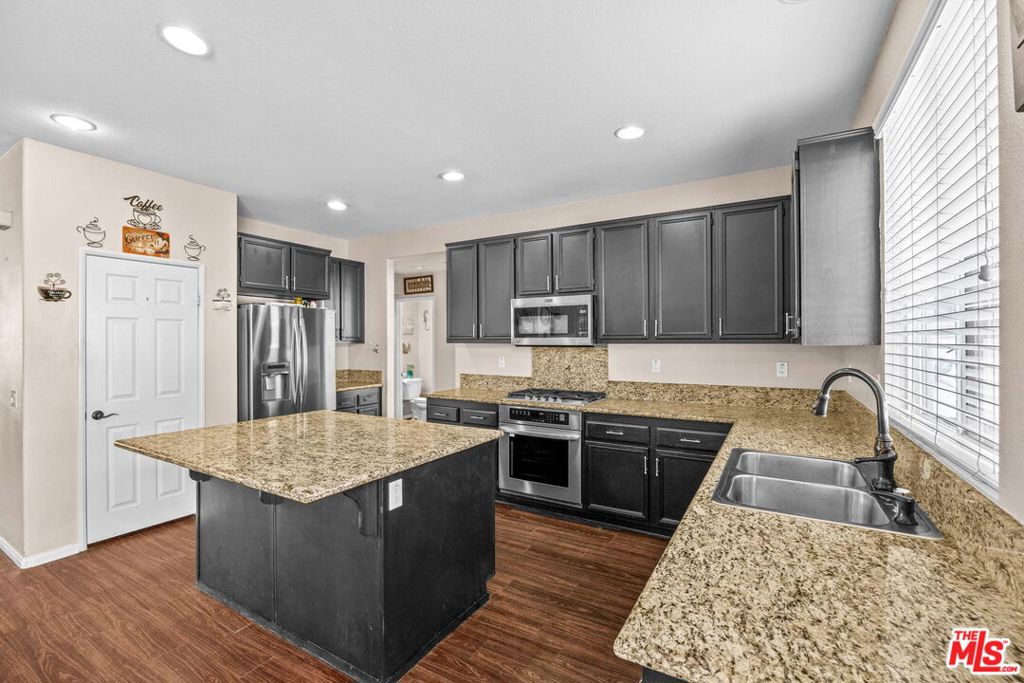 26692 Rim Creek Path, Unit PATHWAY Menifee, CA 92584 - Photo 10 of 41 a kitchen with stainless steel appliances granite countertop a stove a sink dishwasher and a refrigerator with wooden floor