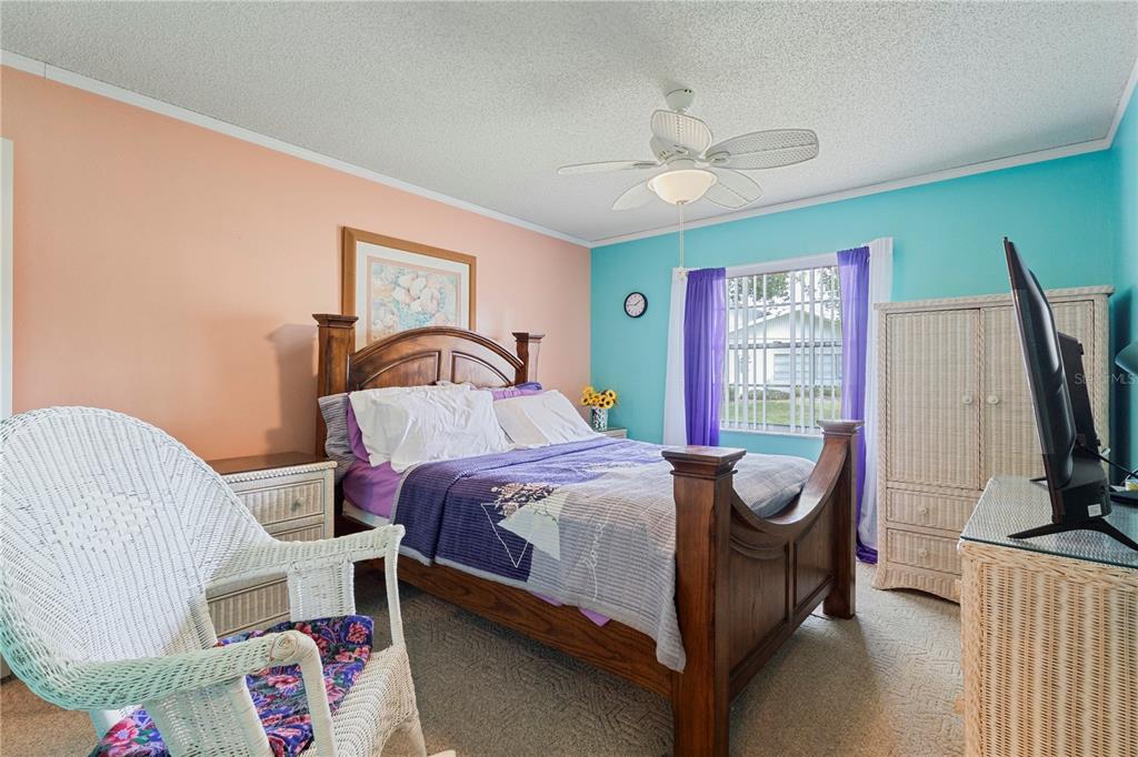 409 Feltham Trail, Unit B Sun City Center, FL 33573 - Photo 15 of 34 a bedroom with a bed and a flat tv screen on dresser
