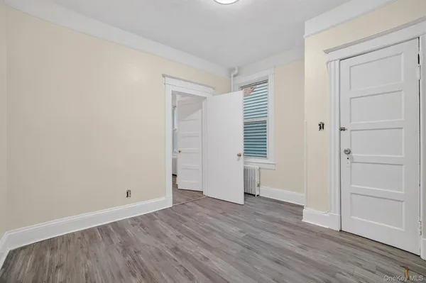 a view of an empty room with wooden floor and closet