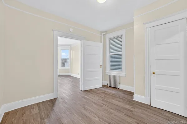 an empty room with wooden floor & closet area