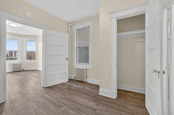 an empty room with wooden floor & closet area
