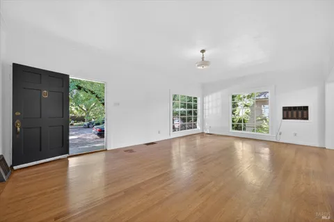an empty room with wooden floor cabinet and windows