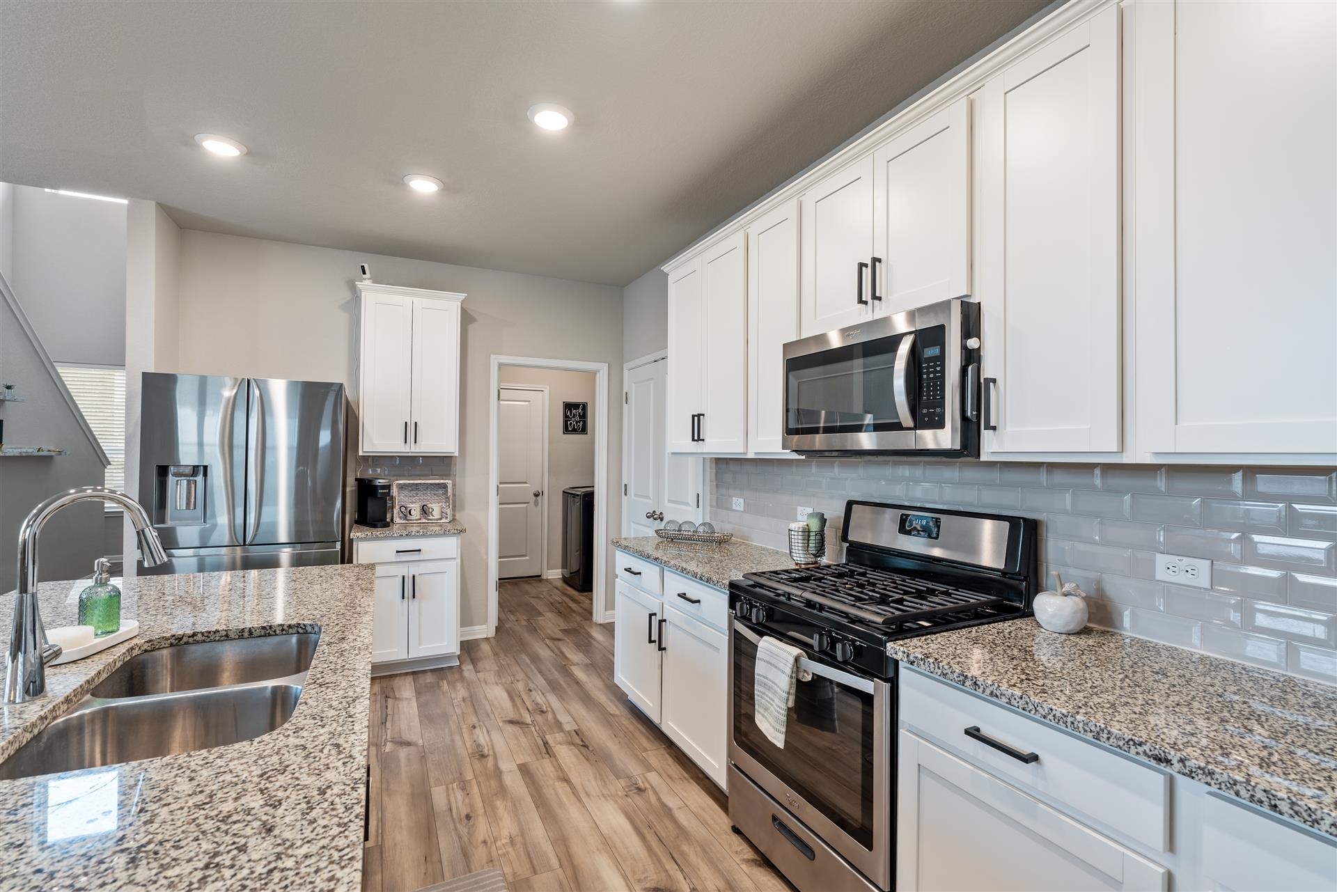 331 Mountain Valley Street Georgetown, TX 78628 - Photo 11 of 40 Kitchen with stainless steel appliances, white cabinets, light wood finished floors, tasteful backsplash, and light stone counters