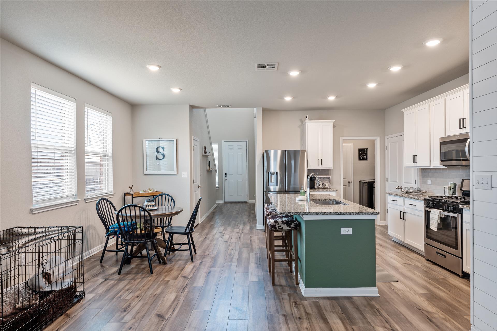 331 Mountain Valley Street Georgetown, TX 78628 - Photo 14 of 40 a kitchen with stainless steel appliances kitchen island granite countertop a stove top oven a sink dishwasher a refrigerator and a dining table with wooden floor