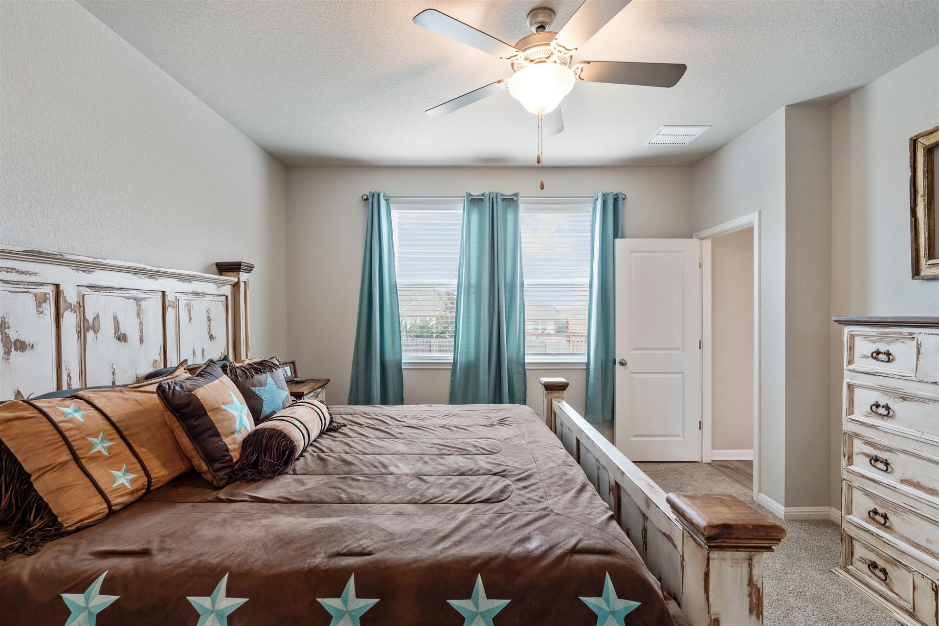 331 Mountain Valley Street Georgetown, TX 78628 - Photo 15 of 40 a bedroom with a large bed and a chandelier