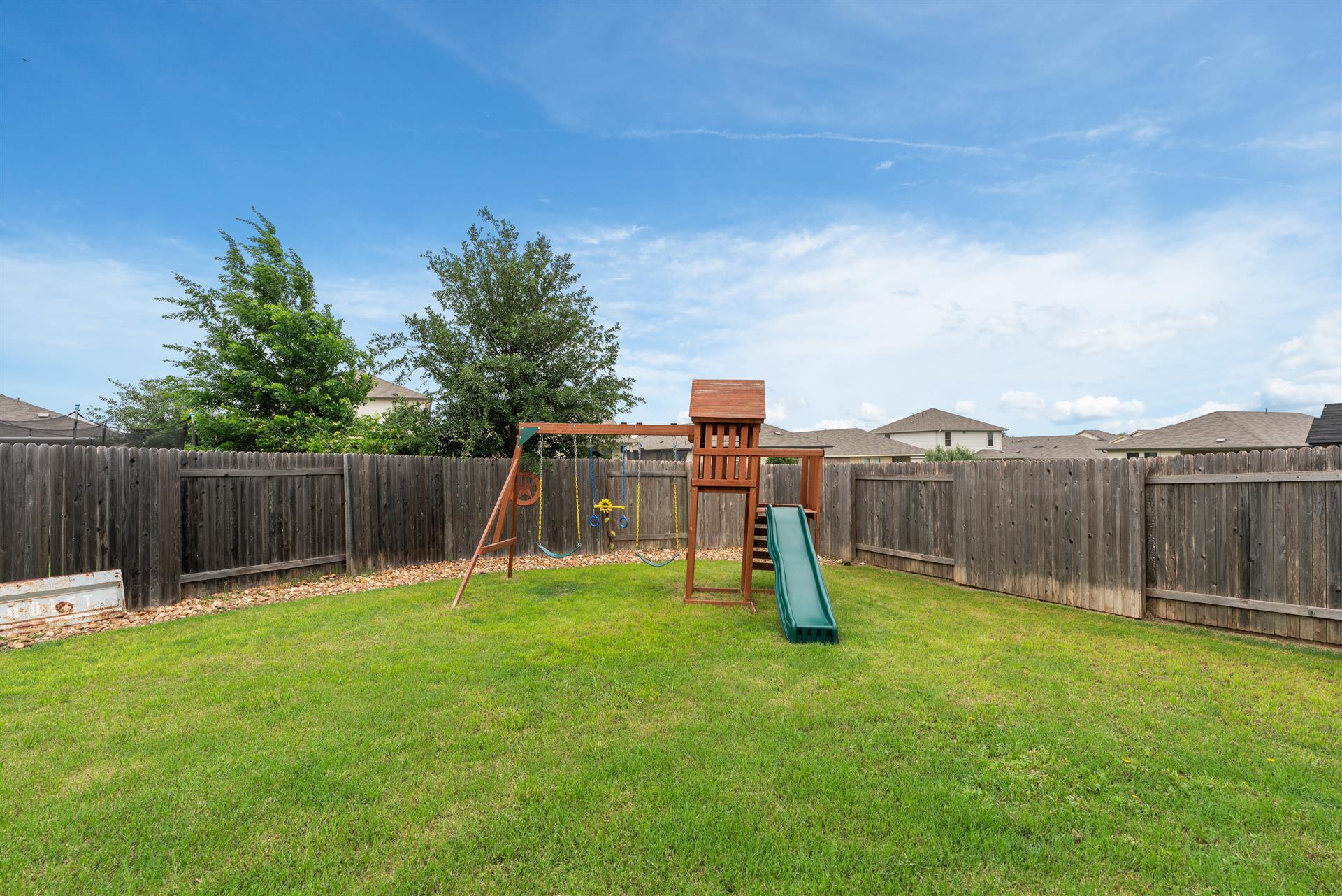 331 Mountain Valley Street Georgetown, TX 78628 - Photo 34 of 40 Spacious backyard featuring a wooden privacy fence, a wooden playset with a slide and swing, and a large expanse of green lawn