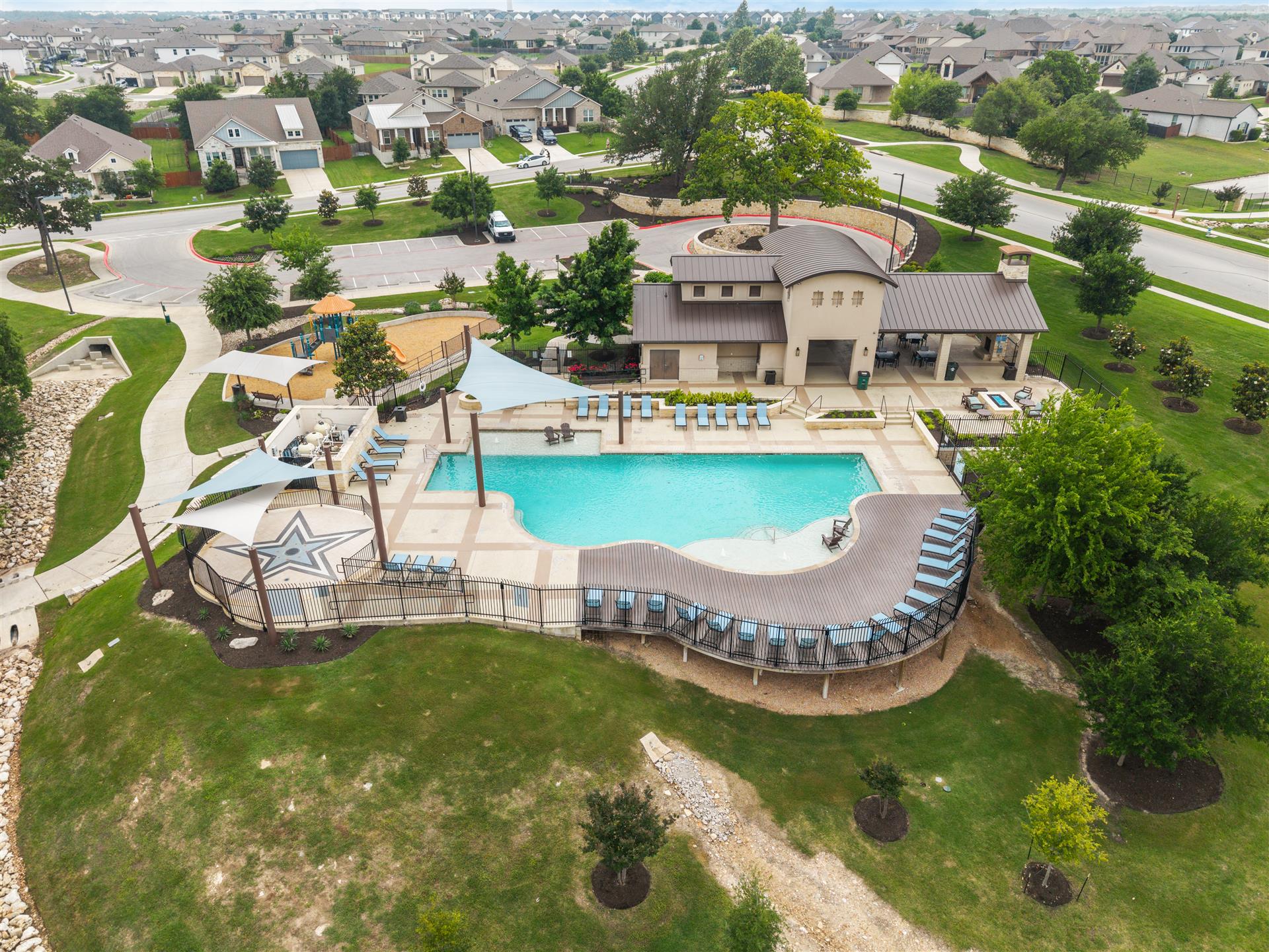 331 Mountain Valley Street Georgetown, TX 78628 - Photo 38 of 40 Community amenity center featuring a large swimming pool with ample lounge seating, a covered outdoor pavilion, a playground, and a walking path surrounded by green landscaping