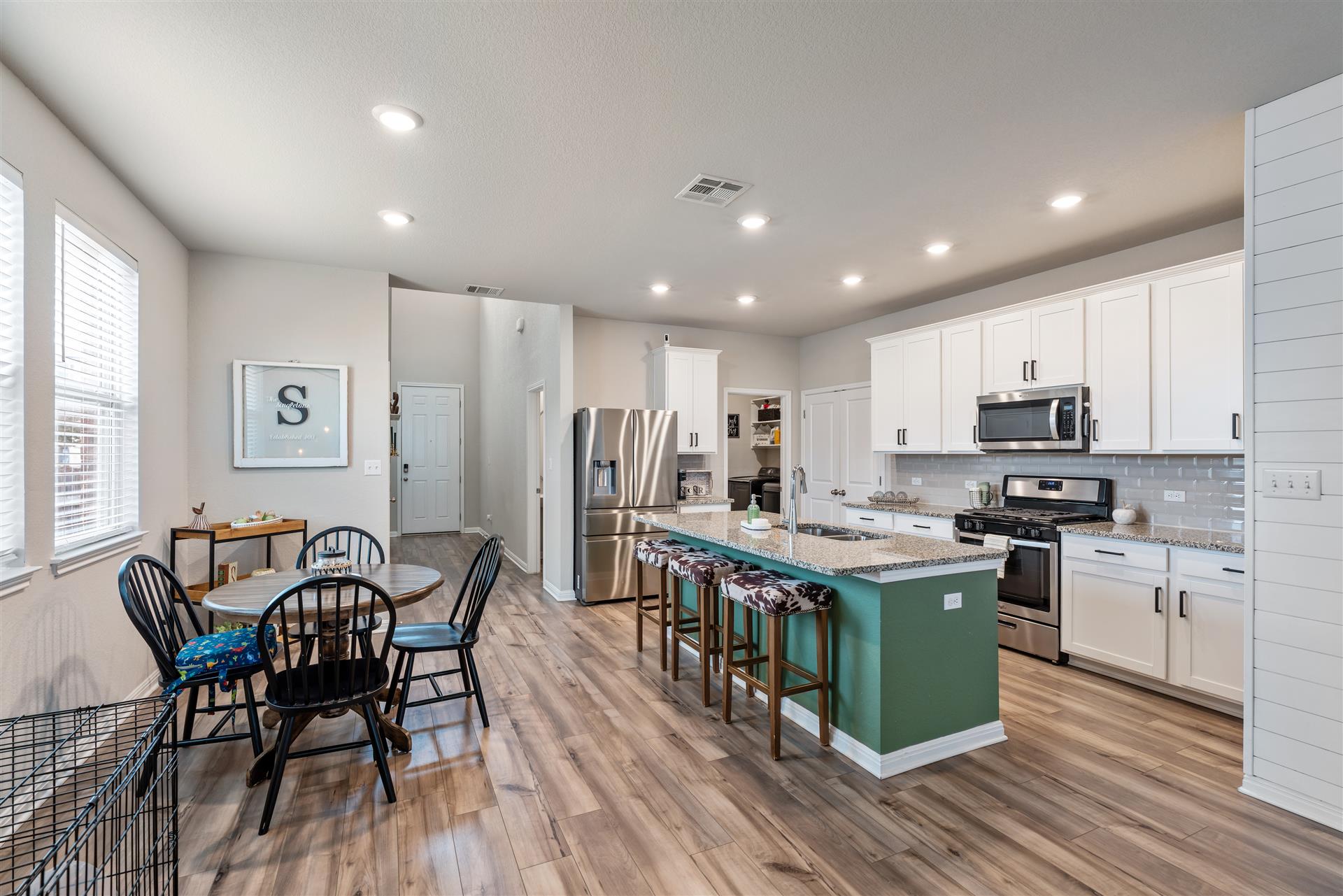 331 Mountain Valley Street Georgetown, TX 78628 - Photo 8 of 40 Gourmet kitchen with stainless steel appliances, granite counters, a center island with sink, a breakfast bar, and wood-type flooring