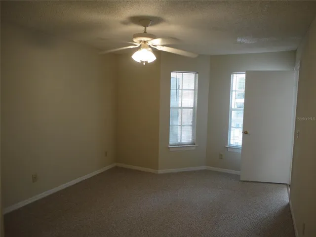 an empty room with windows and chandelier fan