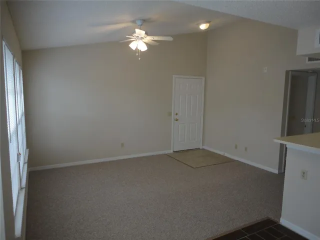 an empty room with windows and fan