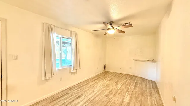 a view of a room with wooden floor and a ceiling fan