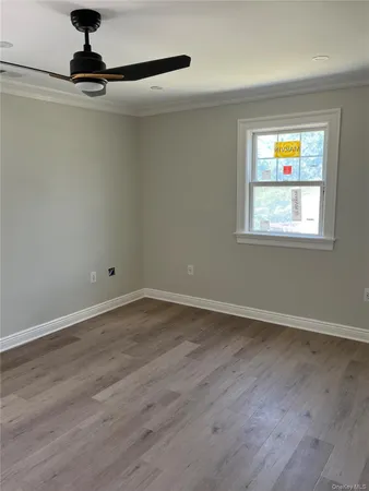 an empty room with wooden floor cabinet and windows