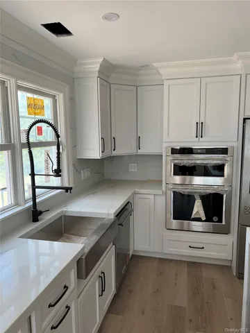 a kitchen with granite countertop white cabinets and stainless steel appliances