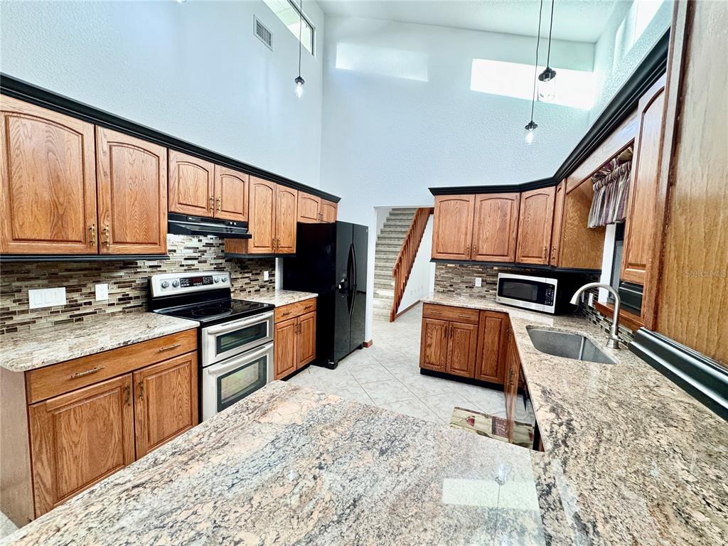6068 Tidwell Street North Port, FL 34291 - Photo 36 of 92 a kitchen with stainless steel appliances granite countertop a stove a sink dishwasher a refrigerator oven with granite countertops and cabinets