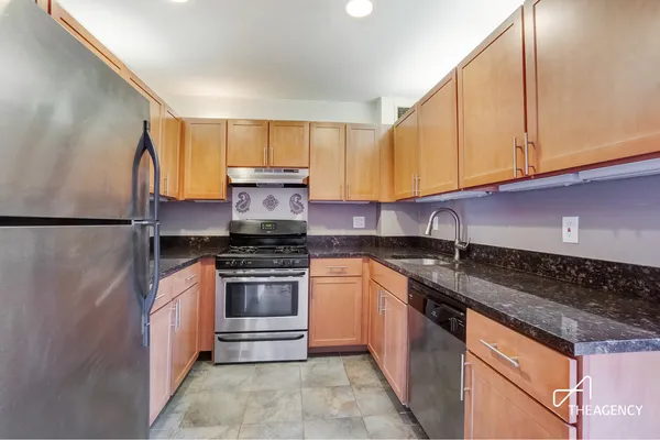 a kitchen with stainless steel appliances granite countertop a stove a sink and a refrigerator