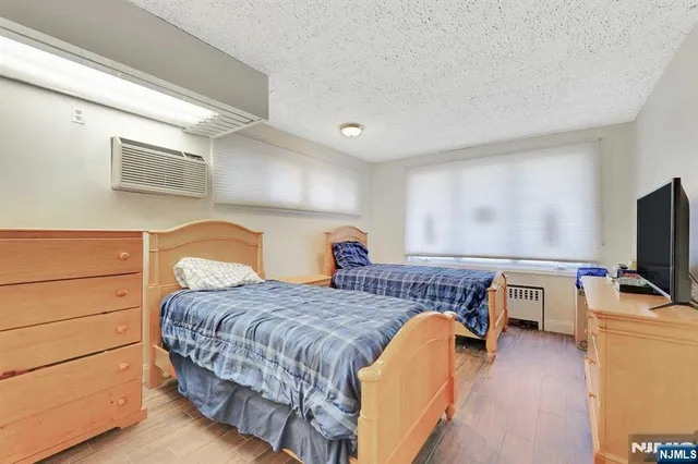 a bedroom with a bed and a flat tv screen on dresser
