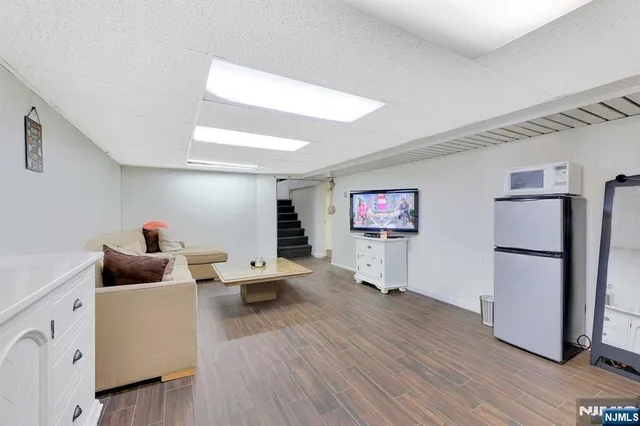 a living room with furniture and a refrigerator