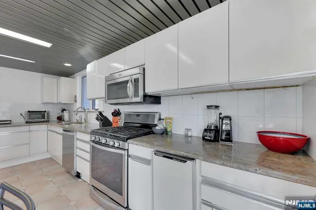 a kitchen with stainless steel appliances granite countertop a sink a stove and cabinets