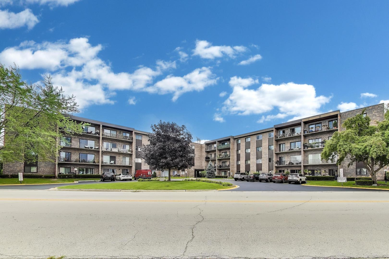 701 West Huntington Commons Road, Unit 418 Mount Prospect, IL 60056 - Photo 2 of 10 a view of a house with a big yard and large trees
