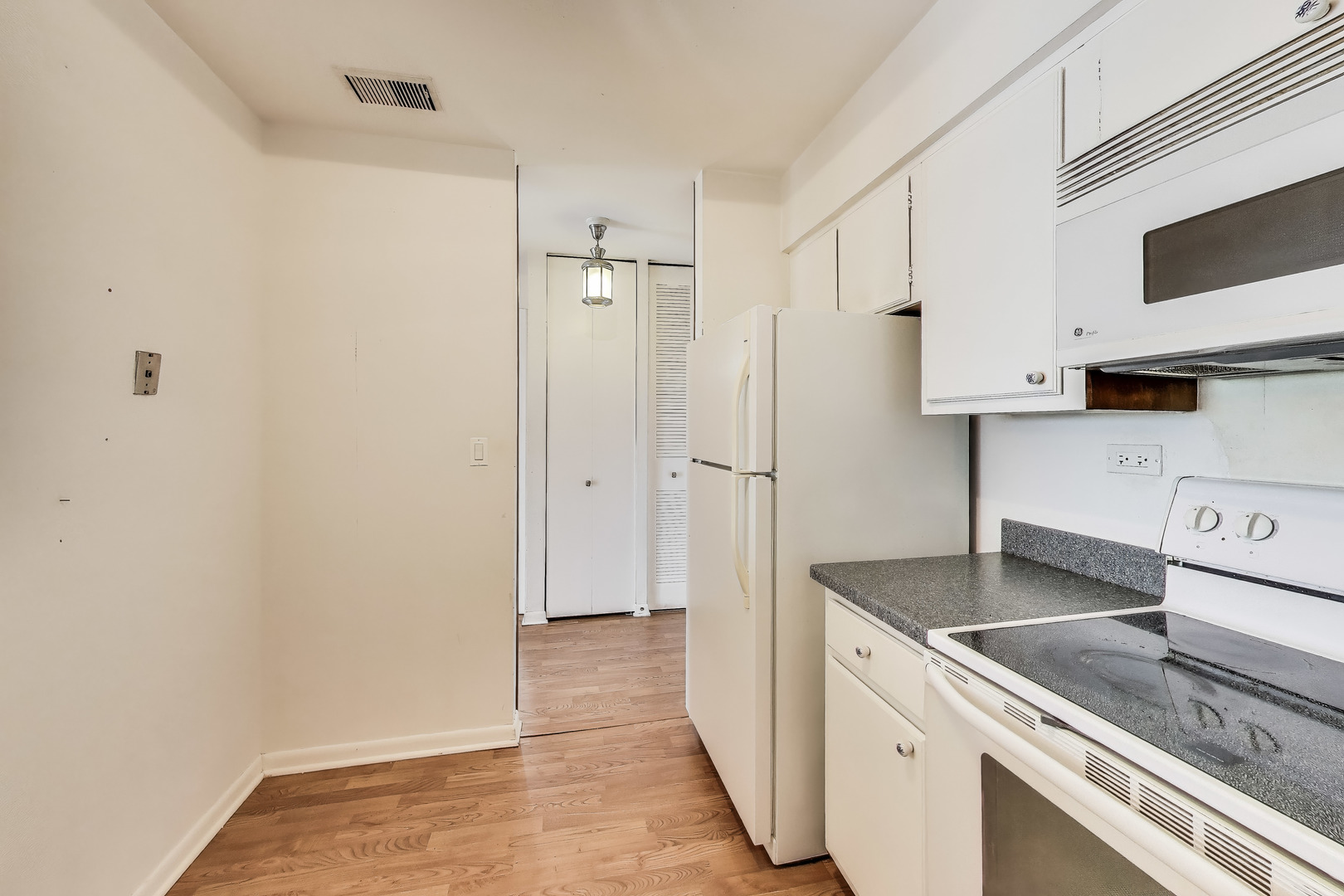 701 West Huntington Commons Road, Unit 418 Mount Prospect, IL 60056 - Photo 6 of 10 a kitchen with granite countertop a sink stove and refrigerator