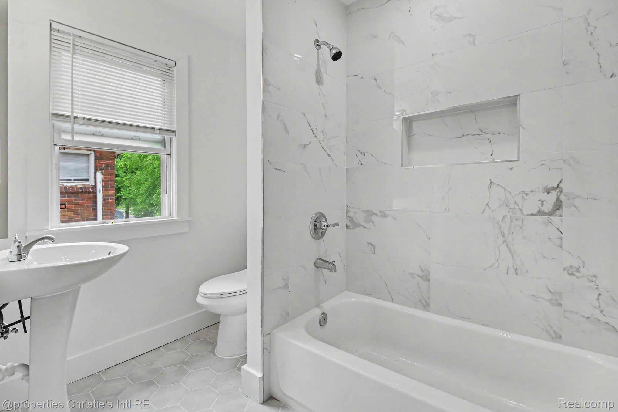 5911 Yorkshire Road Detroit, MI 48224 - Photo 11 of 14 Bathroom featuring a pedestal sink, white toilet, and a bathtub with a shower