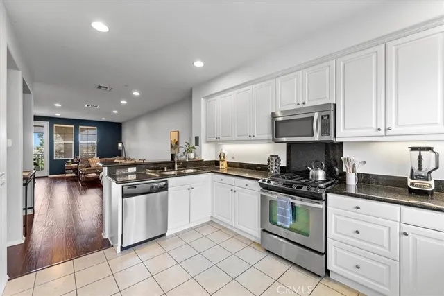 a kitchen with stainless steel appliances granite countertop a stove a sink a refrigerator and white cabinets