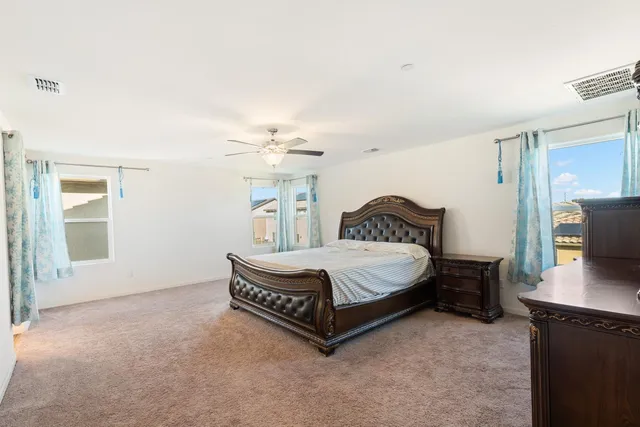 a spacious bedroom with a bed a dresser and a large window