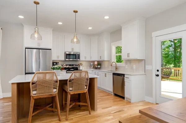 a kitchen with kitchen island granite countertop a table chairs refrigerator and microwave