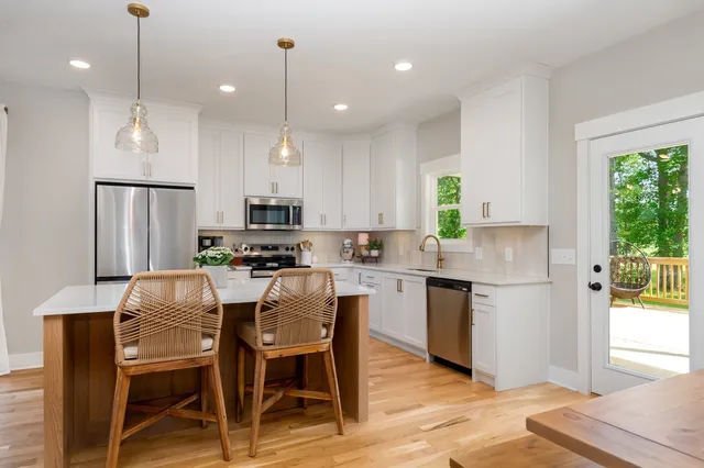 a kitchen with kitchen island granite countertop a table chairs refrigerator and microwave