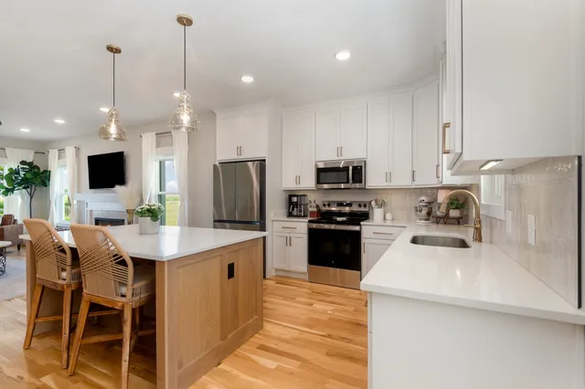 a kitchen with stainless steel appliances kitchen island granite countertop a sink a stove a refrigerator cabinets and a dining table with chairs