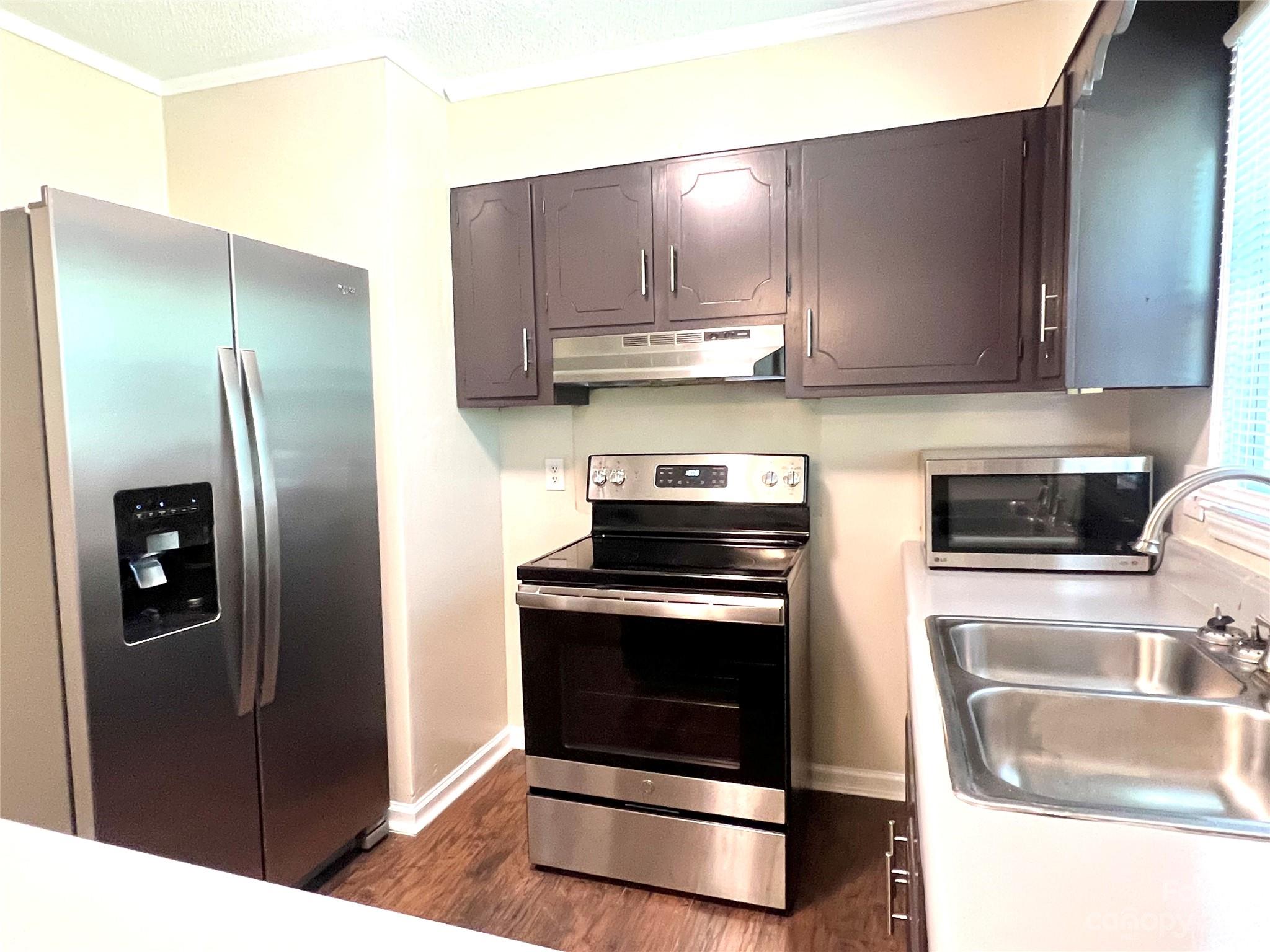 911 Taylor Street Wingate, NC 28174 - Photo 9 of 12 a kitchen with stainless steel appliances granite countertop a refrigerator a stove and a sink with wooden floor