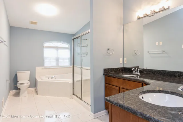 a bathroom with a granite countertop sink a toilet a mirror and bathtub