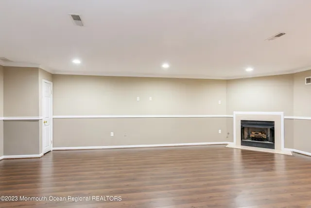 a view of empty room with wooden floor and fireplace