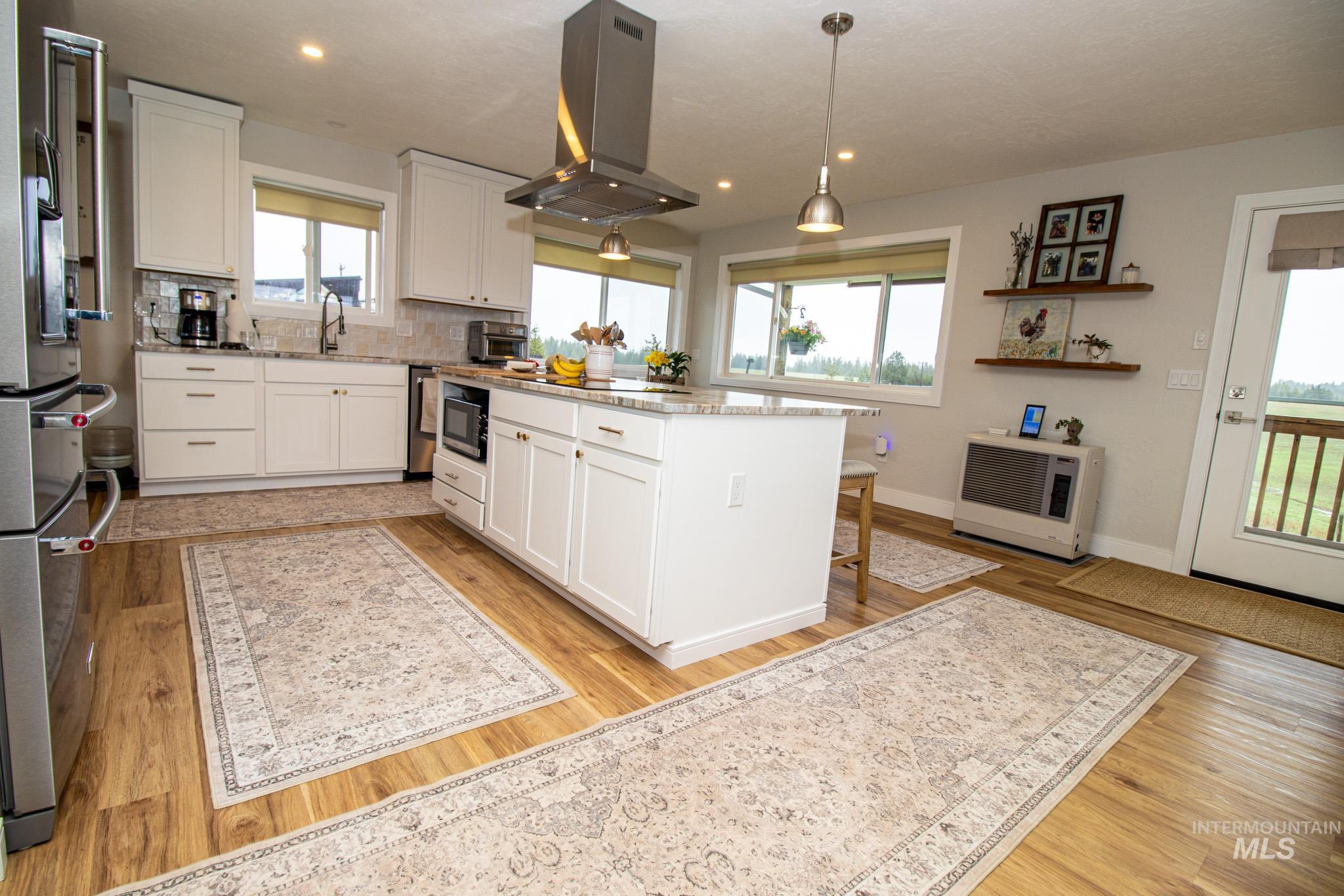 5404 Freeman Creek Road Lenore, ID 83541 - Photo 20 of 50 Kitchen with white cabinetry, island range hood, a kitchen island, light stone countertops, and stainless steel appliances