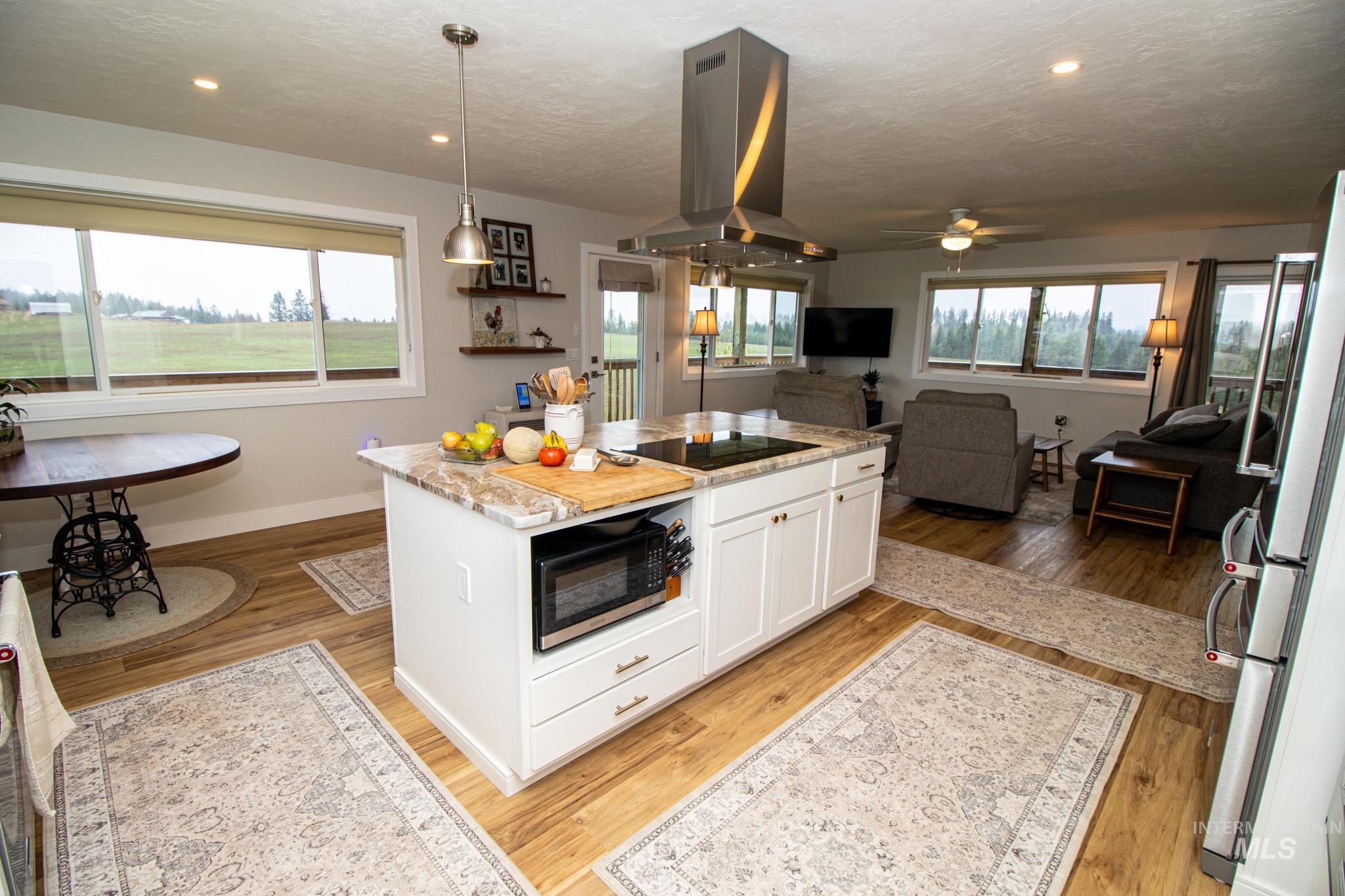 5404 Freeman Creek Road Lenore, ID 83541 - Photo 22 of 50 Kitchen featuring white cabinets, island range hood, a center island, stainless steel appliances, and light wood finished floors