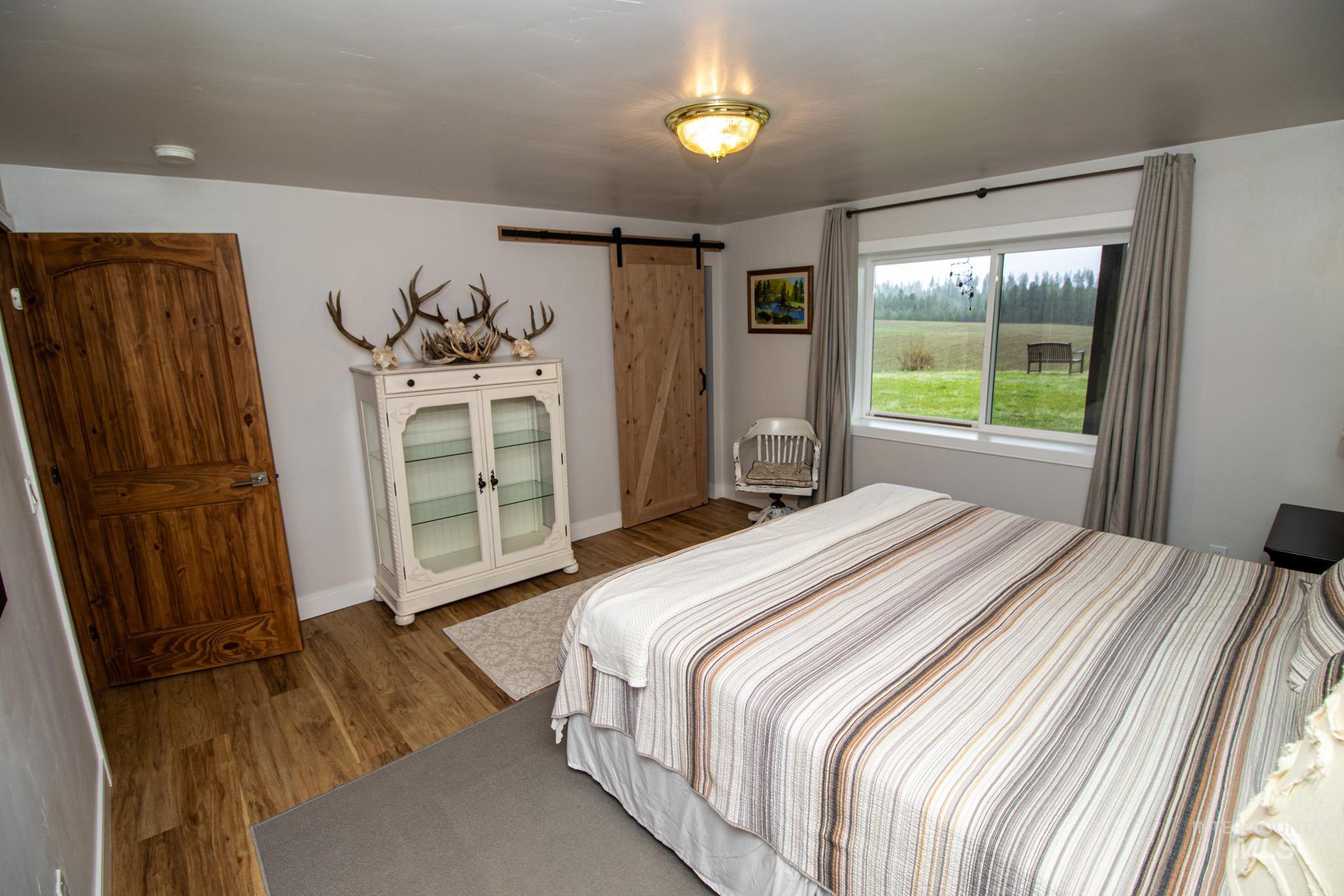 5404 Freeman Creek Road Lenore, ID 83541 - Photo 37 of 50 Bedroom featuring a barn door and wood finished floors
