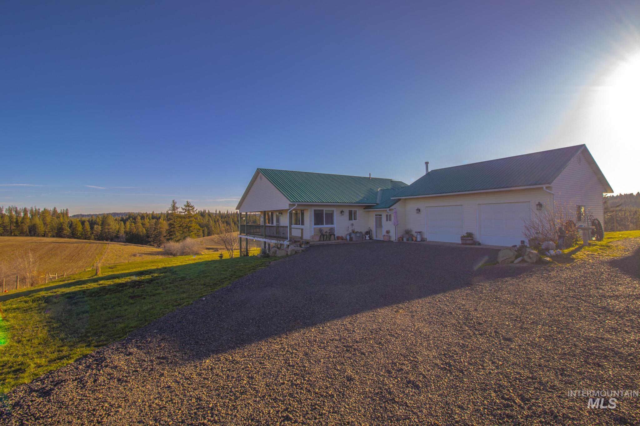 5404 Freeman Creek Road Lenore, ID 83541 - Photo 9 of 50 View of front of house with gravel driveway, a porch, a metal roof, a garage, and a view of rural / pastoral area