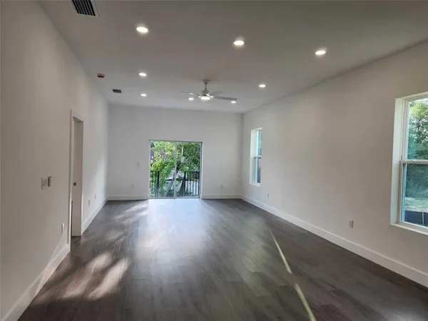 an empty room with wooden floor and windows