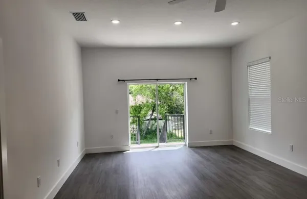an empty room with wooden floor cabinet and windows