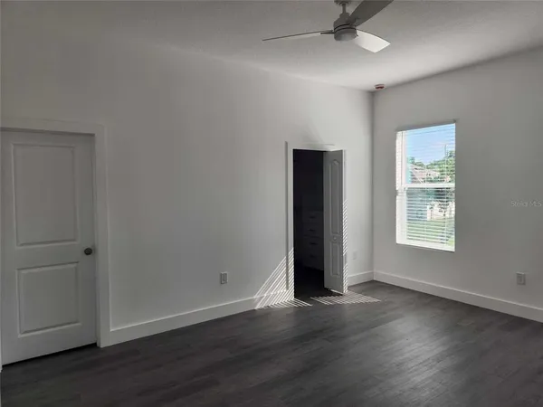 an empty room with wooden floor and windows