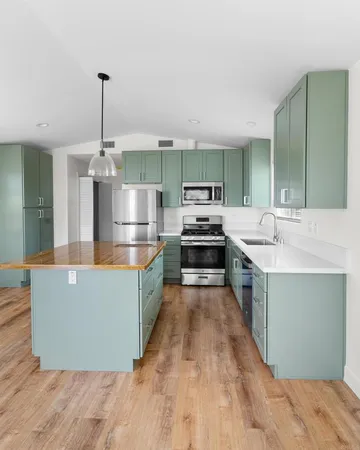 a large kitchen with kitchen island a large counter top and stainless steel appliances