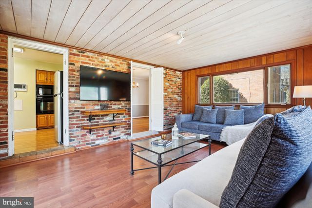 a living room with furniture a flat screen tv and floor to ceiling window