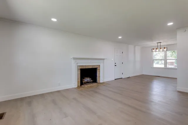 an empty room with windows and fireplace