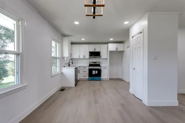 a kitchen with a white cabinets and wooden floor