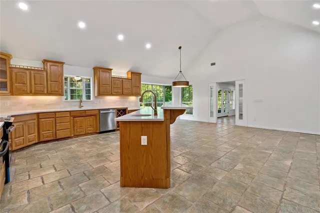 a large kitchen with stainless steel appliances a large counter top a stove a chimney a sink and a refrigerator